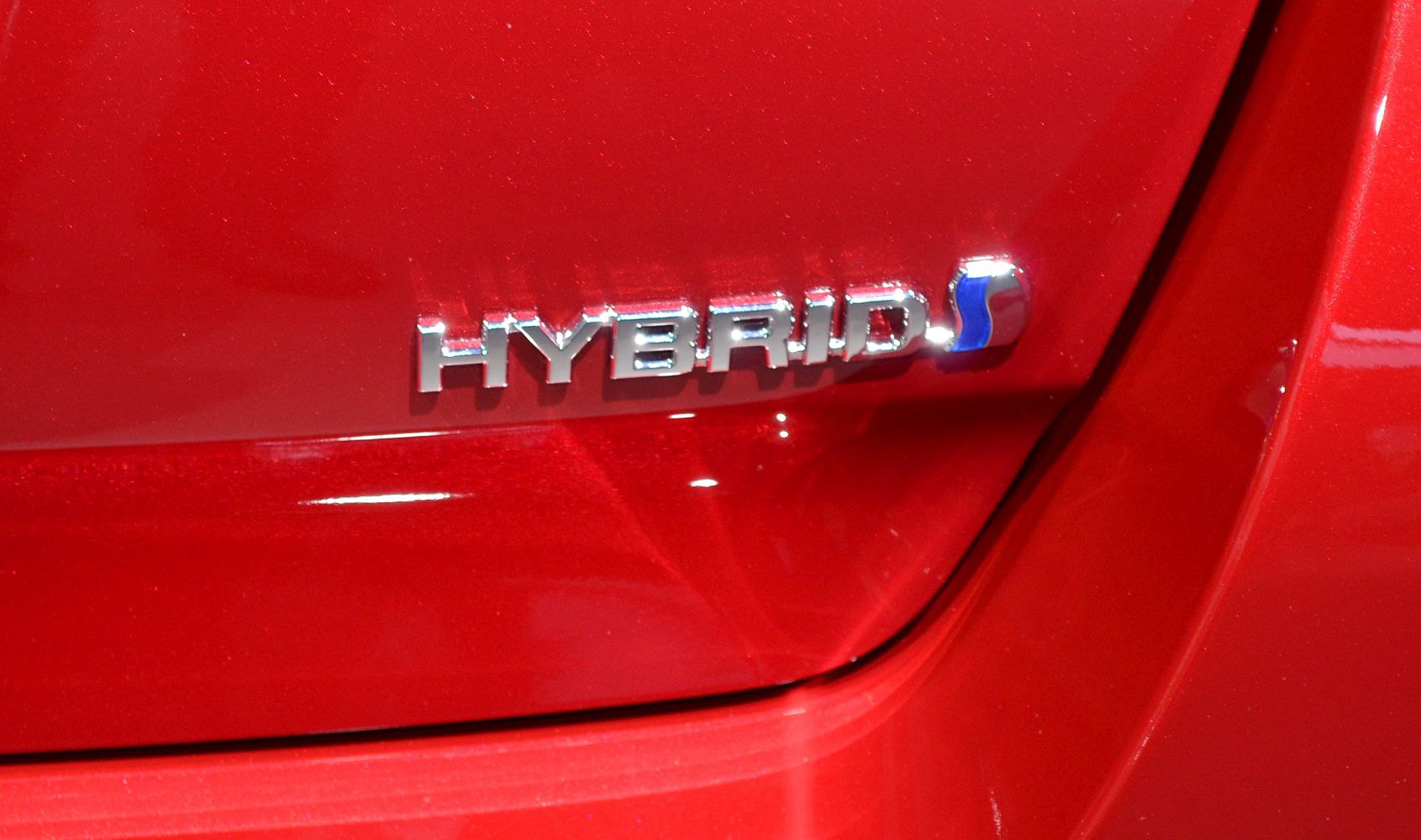 Close-up of hybrid badge on red car panel