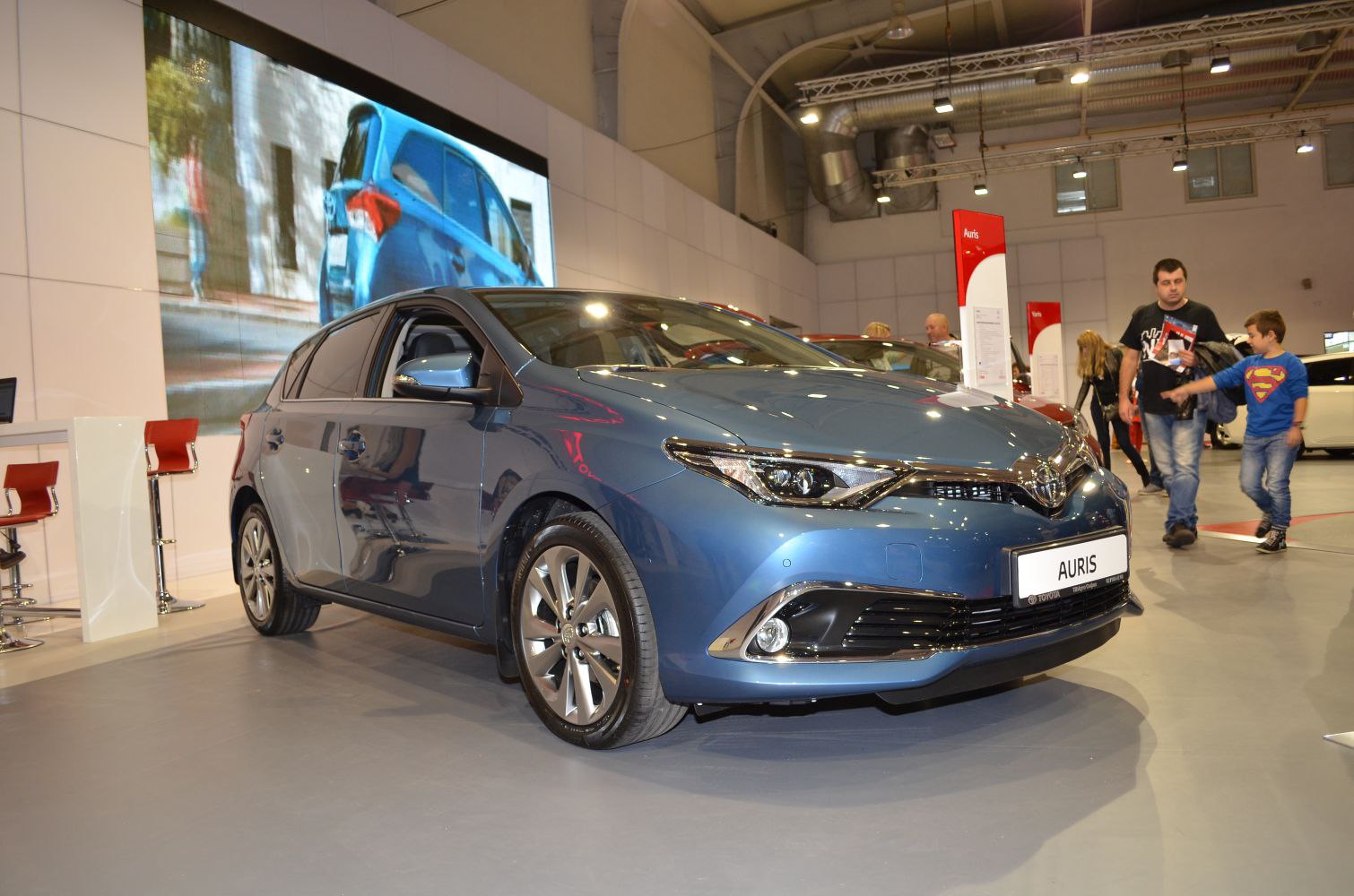 Front and side view of a blue modern hatchback at an indoor auto show