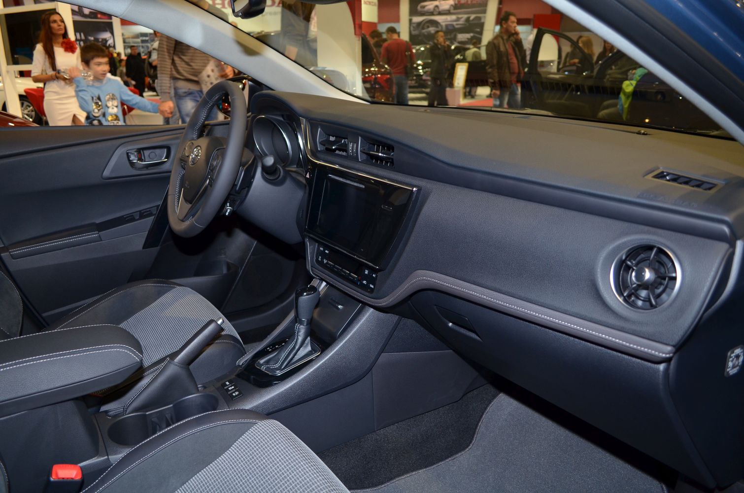 Modern car interior with dashboard touchscreen, steering wheel, and fabric seats.