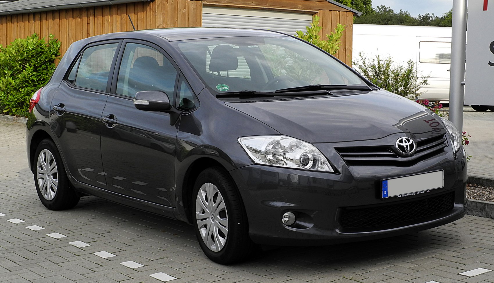 Front-side view of dark hatchback with headlights and grille