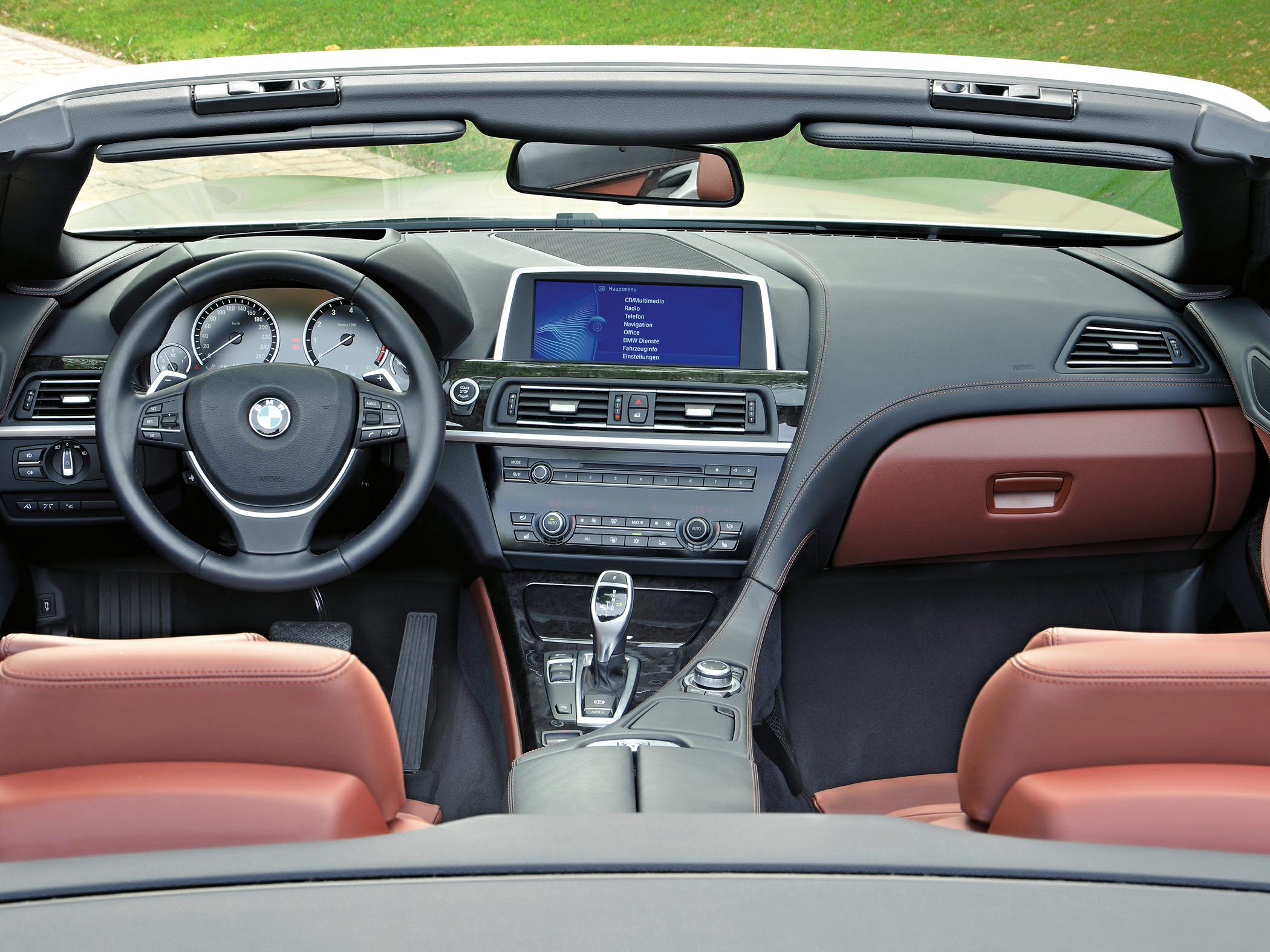 Dashboard and steering wheel of luxury convertible with infotainment screen.
