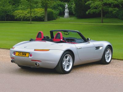 Rear view of a silver convertible roadster with dual exhaust and red interior
