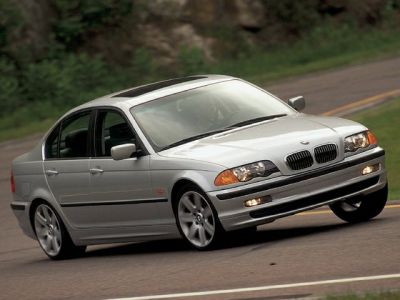 Front side view of BMW 3 Series E36 sedan in motion with sporty stance.