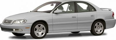 Silver sedan front side view with alloy wheels and classic body lines.