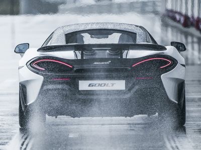 Rear view with illuminated taillights and rear wing in wet conditions