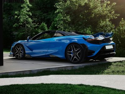 Blue convertible sports car with active rear wing and performance wheels.