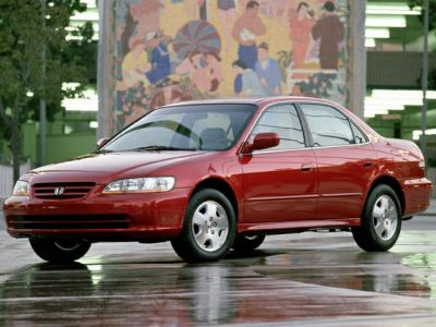 Red four-door sedan with alloy wheels and smooth design on wet reflective surface