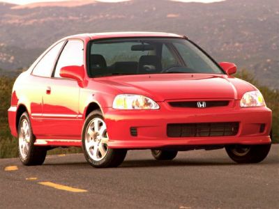 Front side view of a red coupe with alloy wheels and clear headlights.