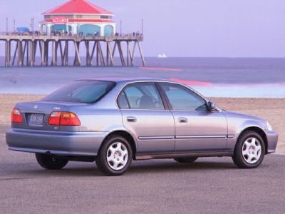 Silver four-door sedan with alloy wheels parked near an ocean pier