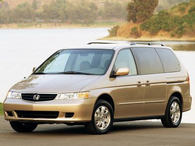 Front side view of a minivan with sliding doors and roof rails