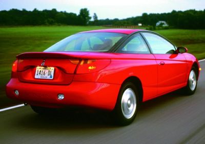 Rear and side view of a red two-door coupe driving on a road