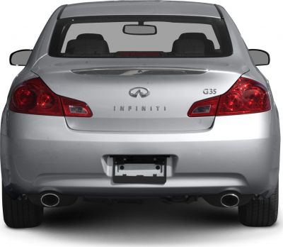 Silver sedan rear with round tail lights and dual exhaust pipes.