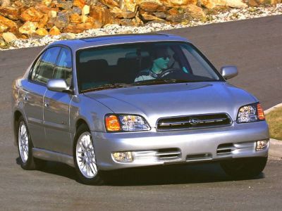 Front view of sedan with silver body and headlights on a paved road