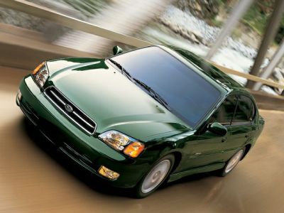 Green sedan with front and side view in motion