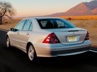 Silver sedan rear view on open road near mountains