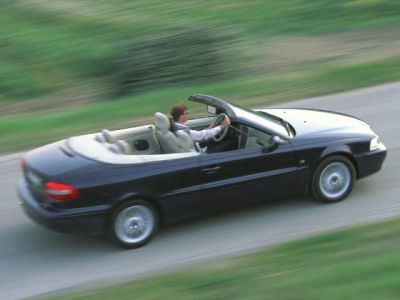 Convertible open-top coupe in motion with driver on road