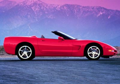 Red convertible sports car with sleek design and alloy wheels in side profile.