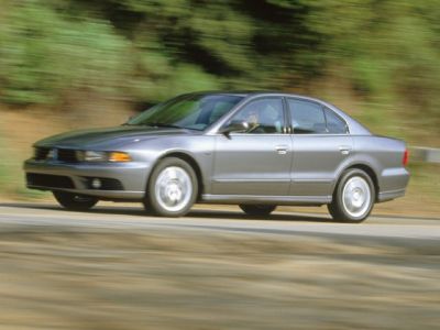 Dynamic silver midsize sedan driving, side profile view