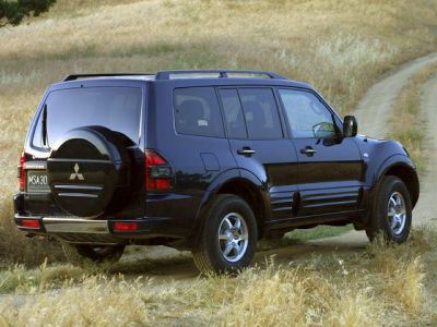 Black SUV rear side view with spare tire and roof rails in a field