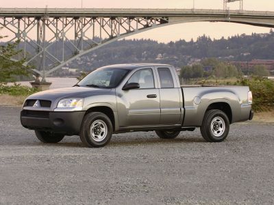 Silver extended cab pickup truck parked on gravel near a bridge