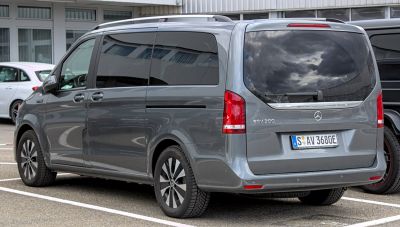 Rear side view of a long electric passenger van with tinted windows and modern taillights