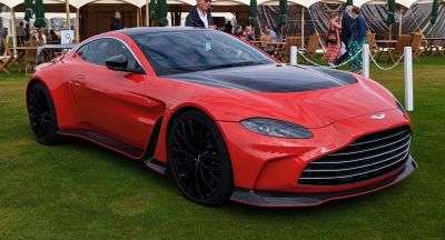 Red sports coupe with black hood, aerodynamic features, and black alloy wheels