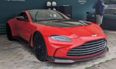 Red sports coupe with black grille, carbon fiber hood, and black alloy wheels