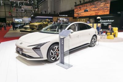 Electric sedan with sleek design and charging station at auto show
