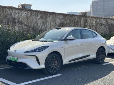 White electric sedan with black multi-spoke wheels and red brake calipers.