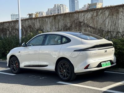 White electric sedan with sleek aerodynamic rear and black alloy wheels.