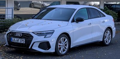 Front side view of sporty sedan with hexagonal grille and LED headlights