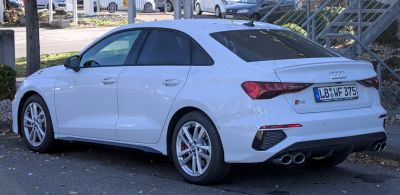 Rear side view, quad exhaust tips, sporty alloy wheels, white sedan