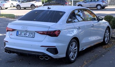 Quad exhaust tips and sleek LED tail lights on a white sedan rear
