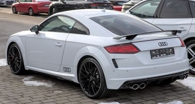 Rear side view of a coupe with black multi-spoke wheels and rear spoiler