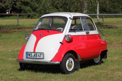 Compact vintage microcar with front-opening door and three-wheel design.