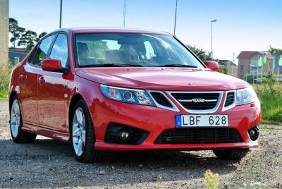 Red sedan front three-quarter view with distinct grille and headlights