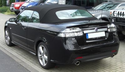 Rear view of convertible with soft top and dual exhaust pipes.