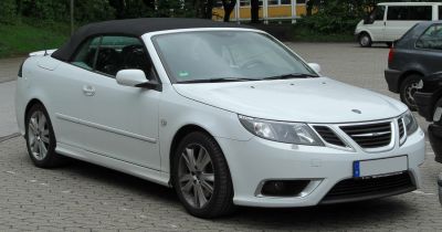 White convertible with black soft top and modern headlights