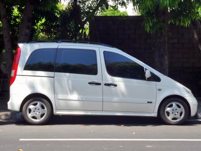 Side view of white MPV with tinted windows and roof rails