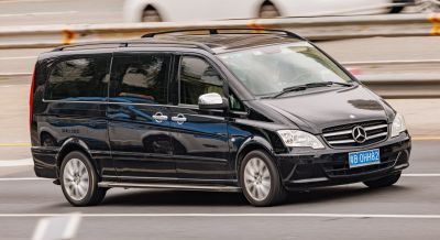 Black minivan with sliding side doors and roof rails driving on road