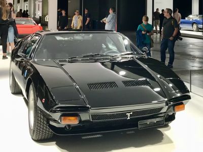 Front view of a sleek black classic sports car with pop-up headlights and vented hood