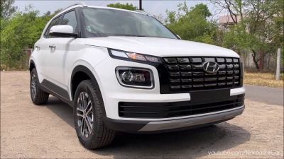 Front grille and headlight design of a white compact SUV.