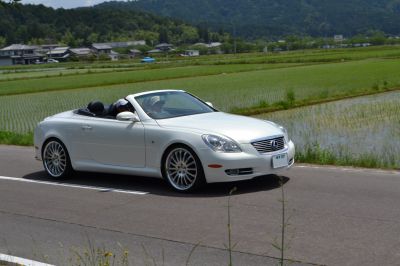 White convertible with sporty alloy wheels driving on rural road