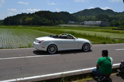 White luxury convertible coupe on countryside road with open roof.