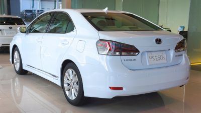 Rear and side view of white Lexus hybrid sedan with distinct tail lights and hybrid badge