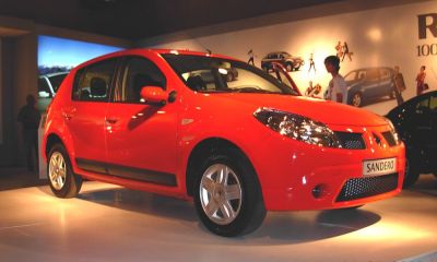 Front left side view of a red compact hatchback with alloy wheels