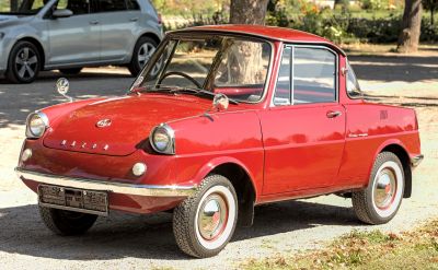 Vintage compact car with round headlights and chrome bumper in red.