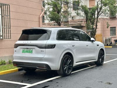 Rear and side profile of a white SUV with tinted windows and multi-spoke wheels