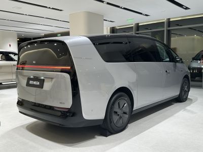 Sleek rear and side of futuristic electric minivan with continuous taillight strip.