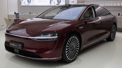 Sleek electric sedan front with advanced headlights and multi-spoke wheels